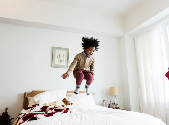 young child jummping on bed